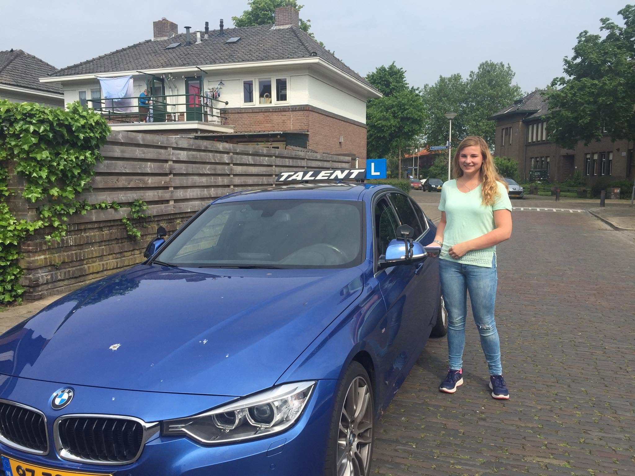 Leerling naast de echte blauwe BMW lesauto van Rijschool Talent